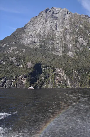 A tourist boat in the distance dwarfed by the side profile of Mitre Peak (1,692m)