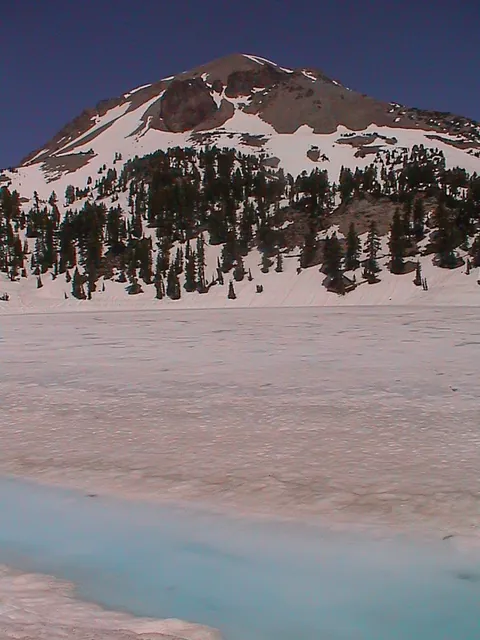 Mount Lassen with a snowy base and gorgeous aquamarine stream running past it