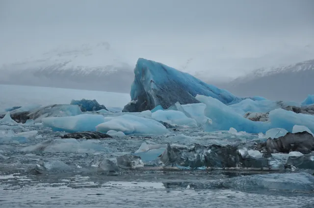 A zoom on a monstrous blue 'berg pointing out of the water. Presumably a big flat bit broken off lifted on its side?