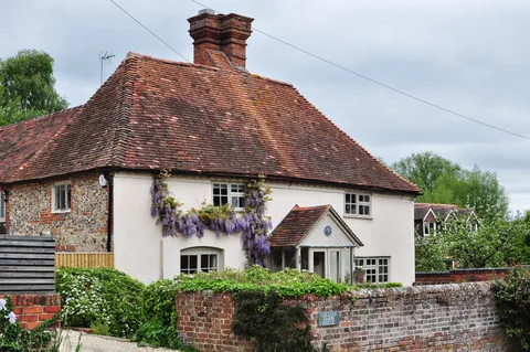 Immaculate cottage with the cream paint and the wysteria growing out front