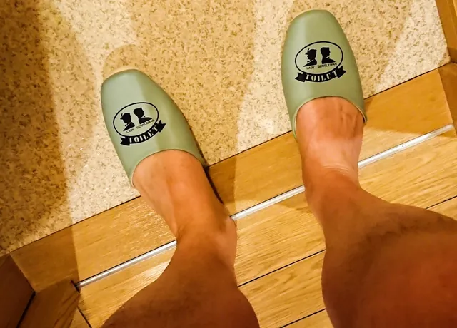 Toilet slippers. They clearly think men are waving their willies around in the cubicle when having a pee, and a pair of slippers are the only defence against it