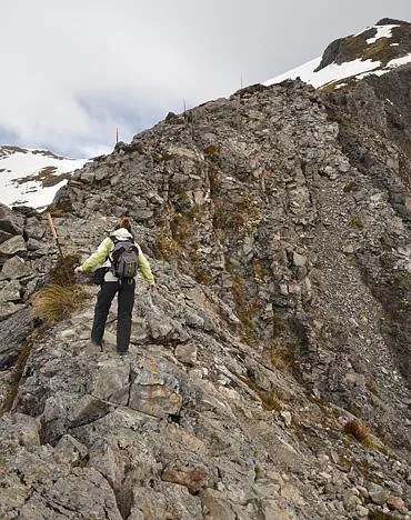 Gill cautious climbing up over a rocky ridge-line